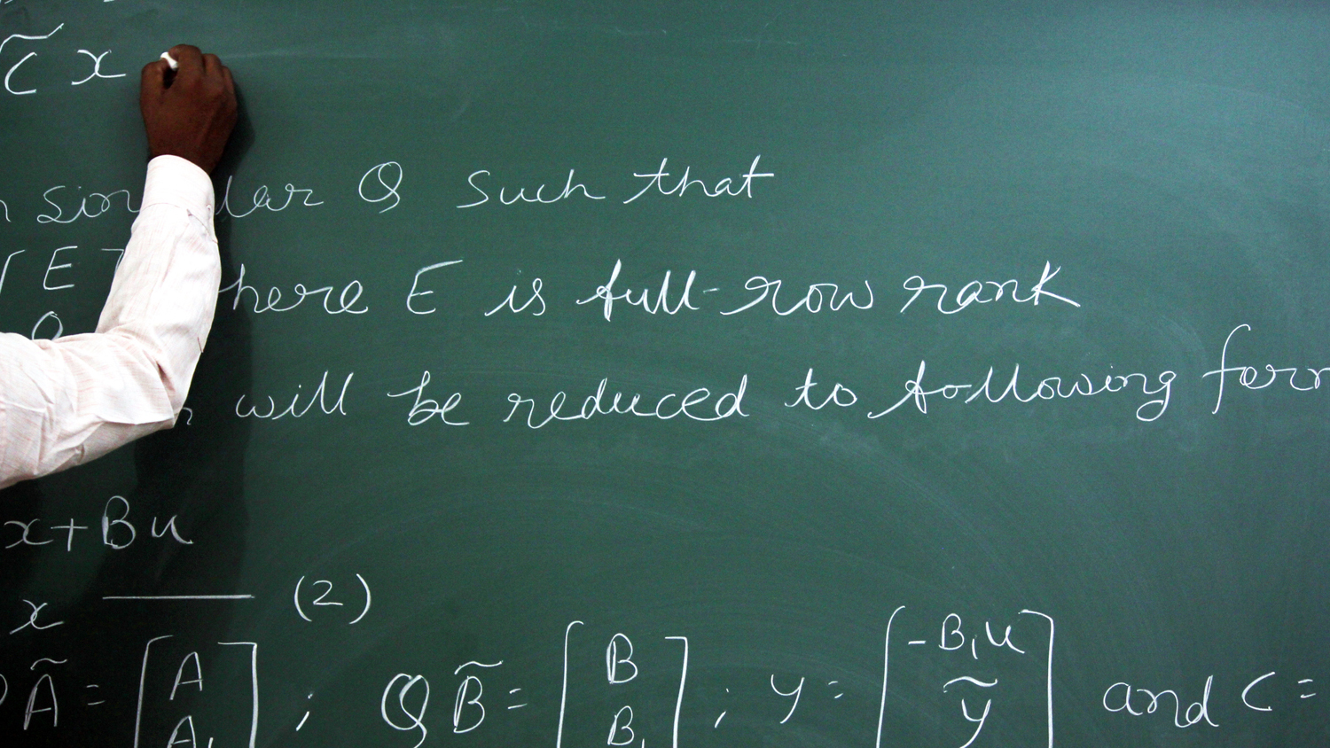 Teacher writing math equations on chalkboard